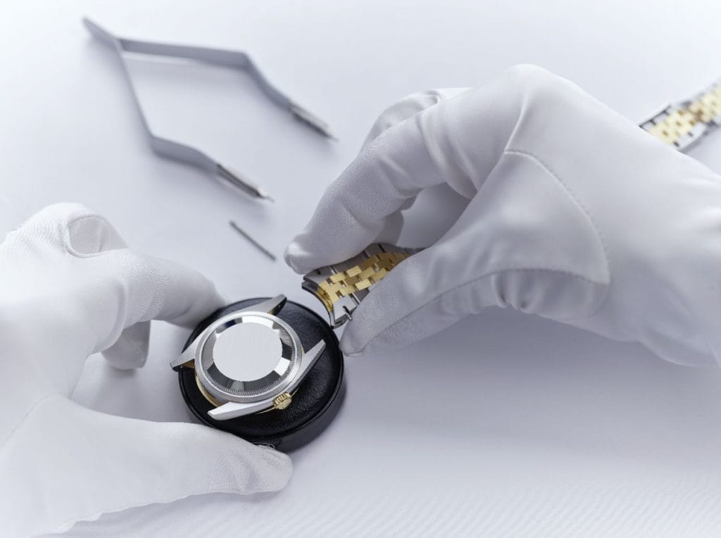 Une fois le fond du boîtier revissé et le bon fonctionnement de la montre vérifié, l'horloger remonte le bracelet sur le boîtier.