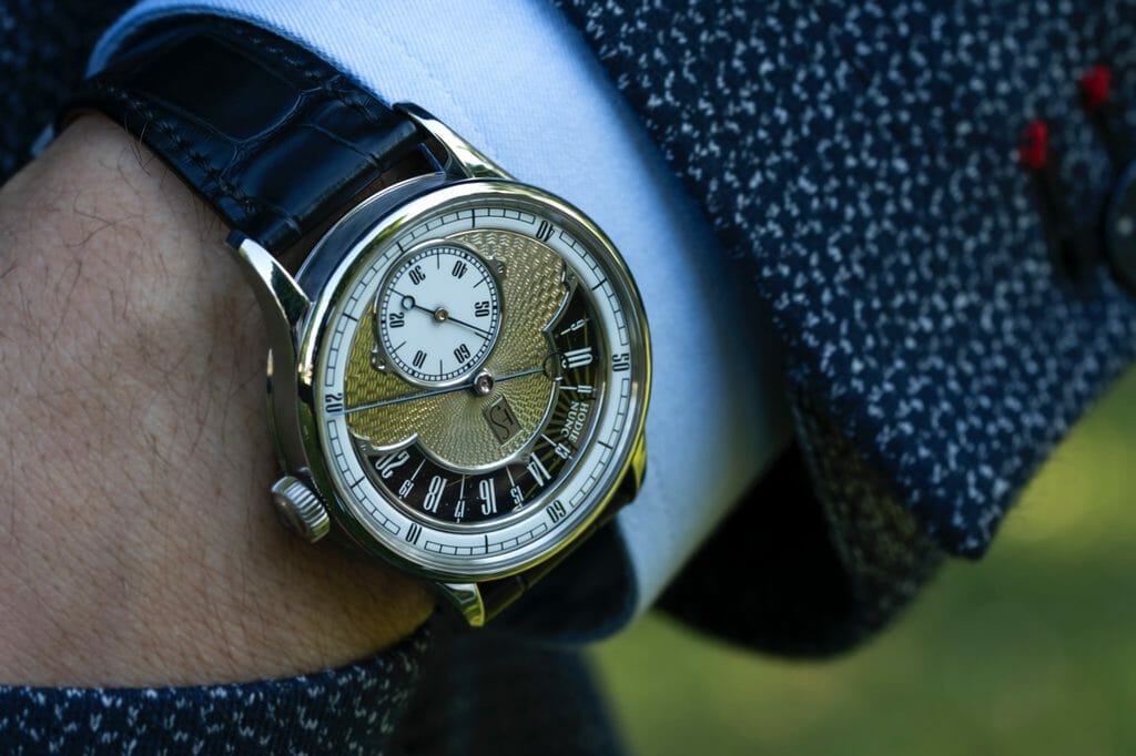 Guichet des heures et des secondes : Acier, trempées-revenues et blanchies main, cerclés. Anglaise et moulures réalisées et polies main, flancs étirés.
Cadran minutes et secondes : Email Grand Feu blanc, déclaques noires brillantes.