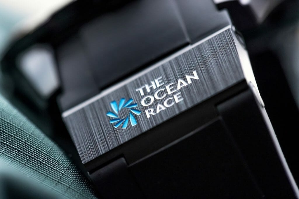 Bracelet en caoutchouc noir avec élément en céramique noire à 6 heures, gravé logo The Ocean Race / Boucle ardillon en céramique noire. 